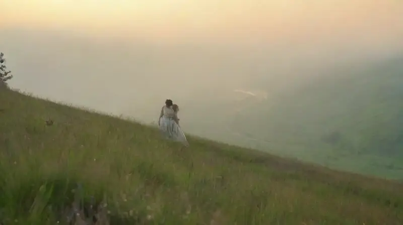 Pareja enamorada observa amanecer en colina